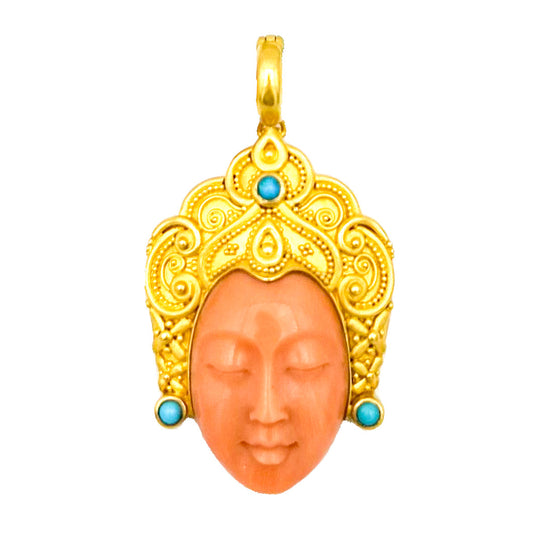 Gold pendant with coral face and turquoise stones on a white background