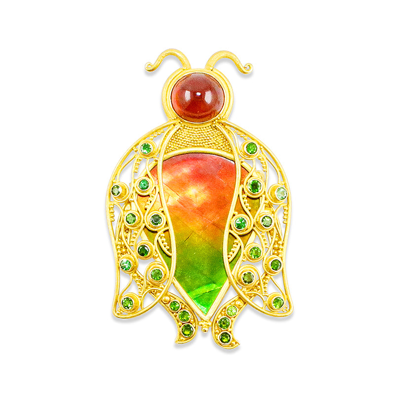 A 22k gold pendant/pin in the shape of a beetle, featuring a large iridescent orange and green ammolite centerpiece, with smaller green Tsavorite garnets set in the wings and a mandarin garnet forming the head.