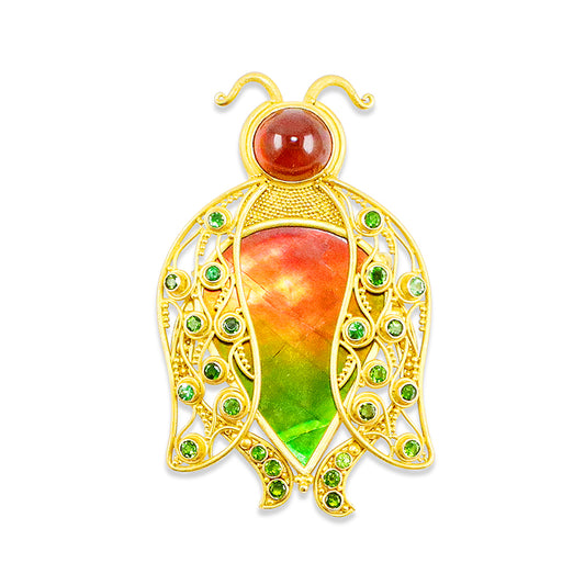 A 22k gold pendant/pin in the shape of a beetle, featuring a large iridescent orange and green ammolite centerpiece, with smaller green Tsavorite garnets set in the wings and a mandarin garnet forming the head.