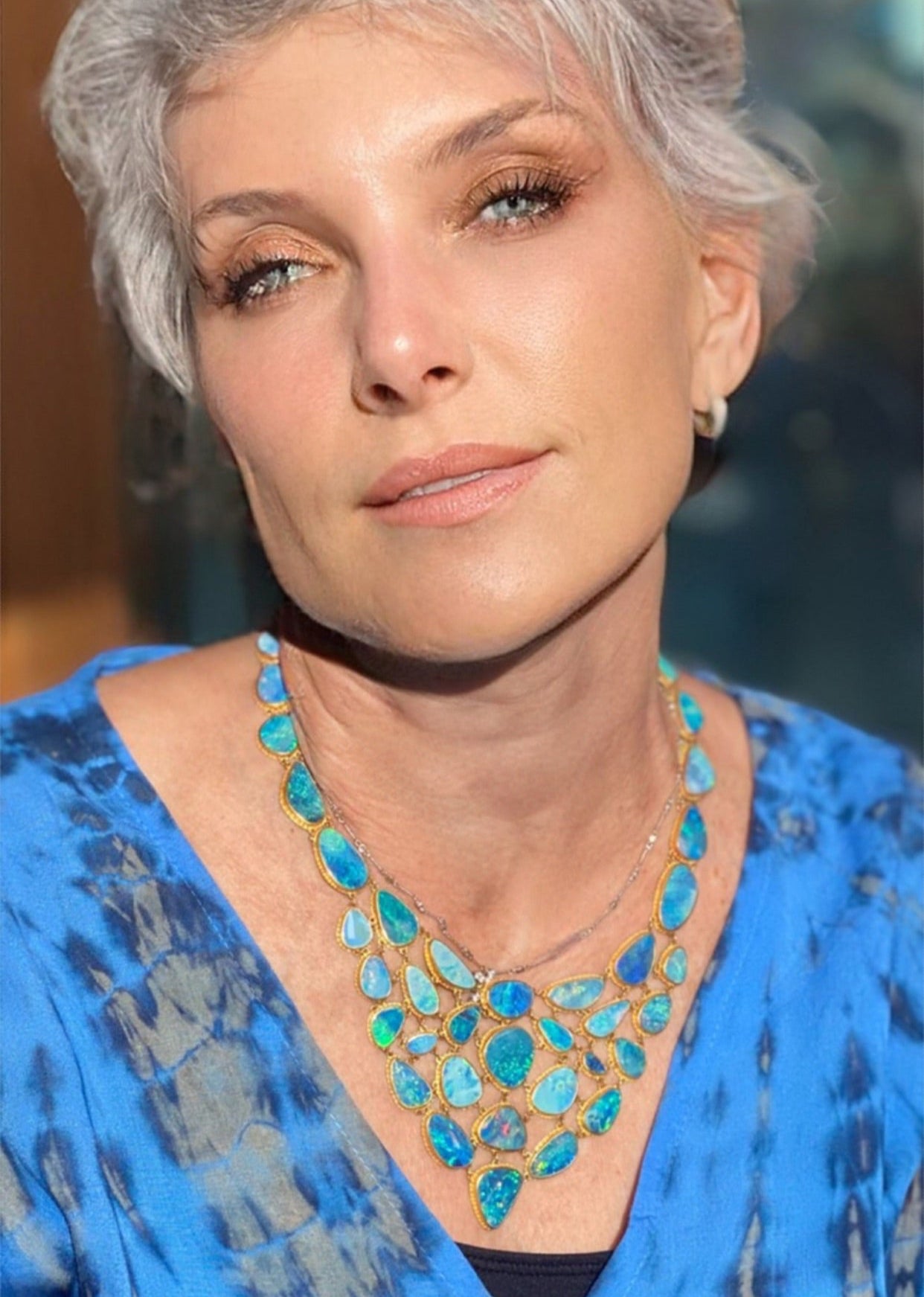 Woman wearing a blue top and turquoise necklace with a blurred background