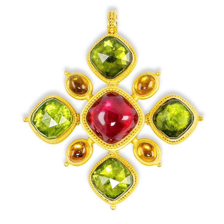 Gold pendant with red and green gemstones on a white background