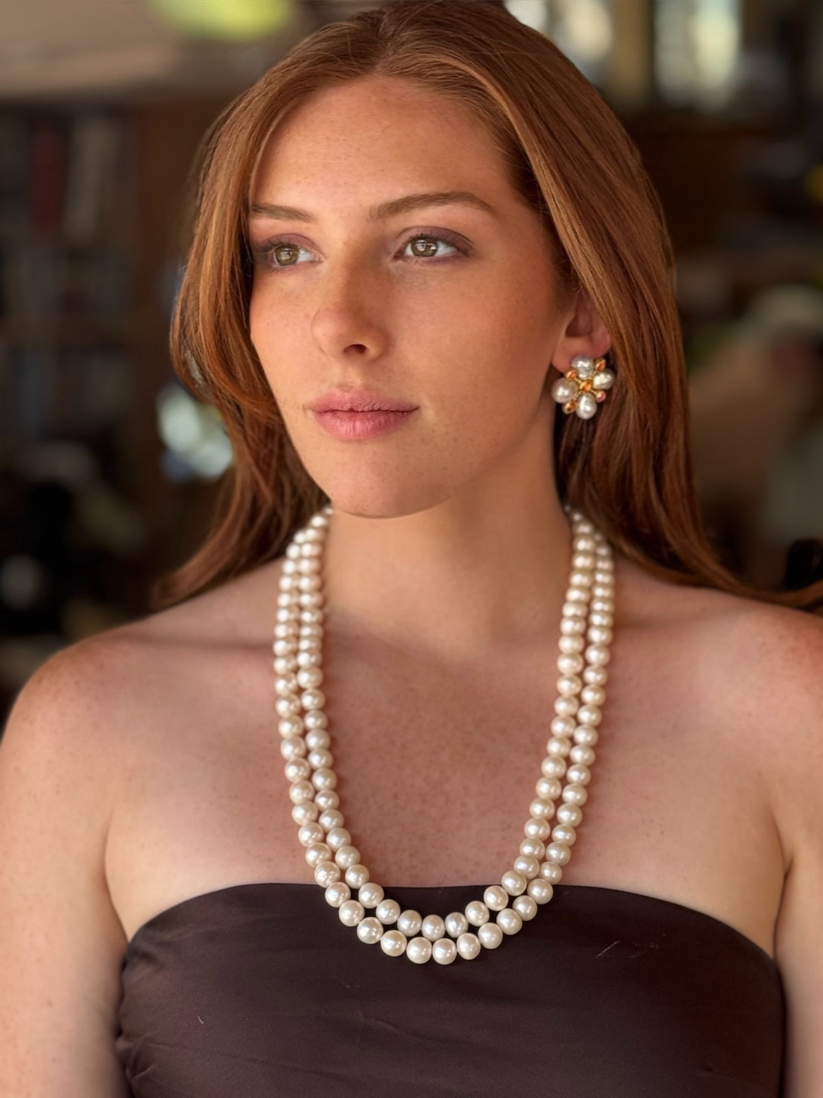Woman wearing a pearl necklace and earrings with a blurred background