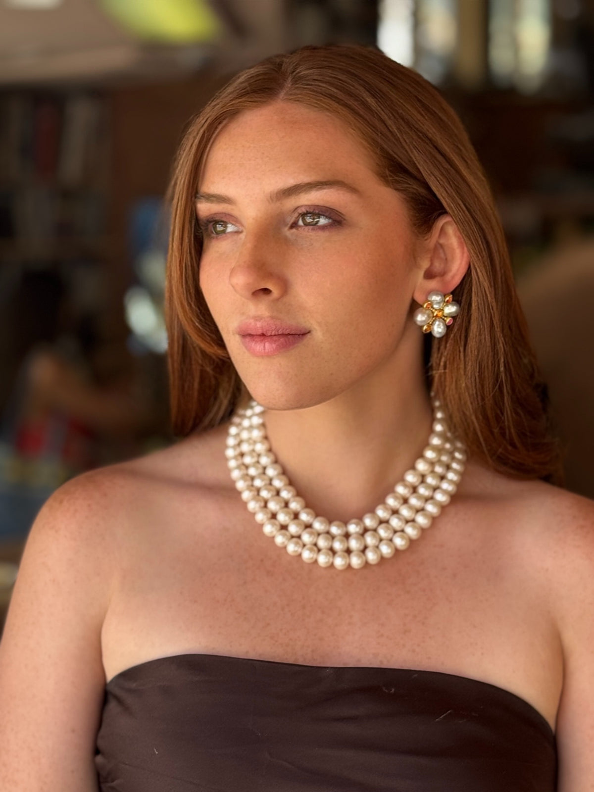Woman wearing a pearl necklace and earrings in an indoor setting