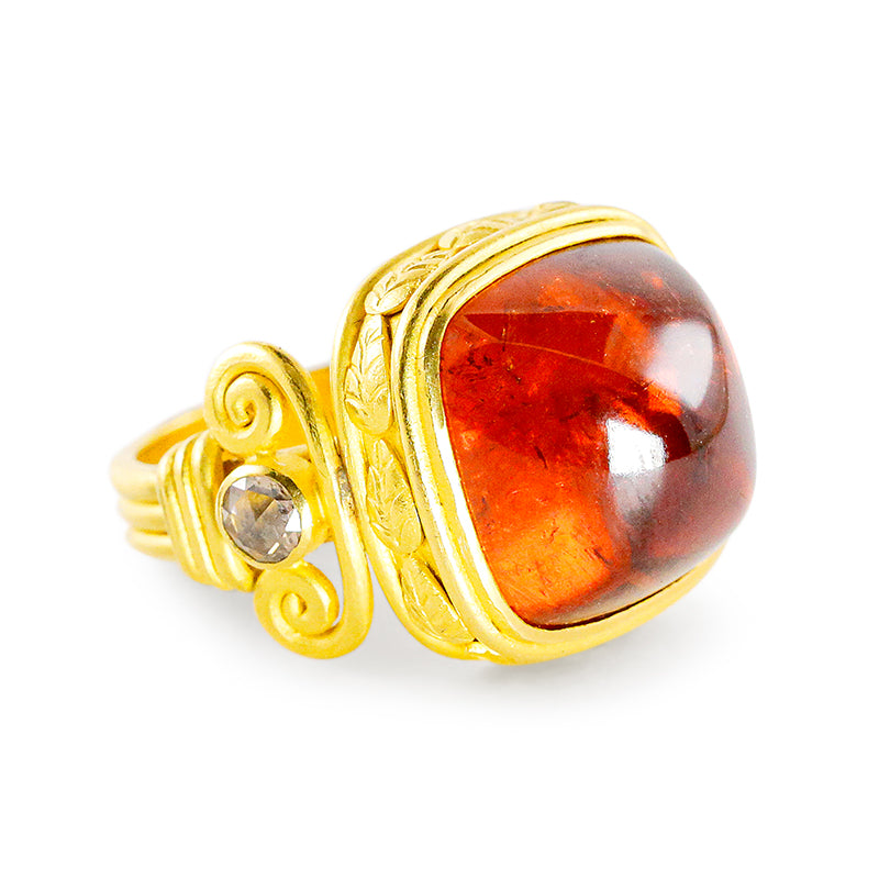 A 22k gold ring with a large hessonite garnet sugarloaf cabochon center stone and small rose cut champagne diamonds on the sides, featuring column-like design elements.
