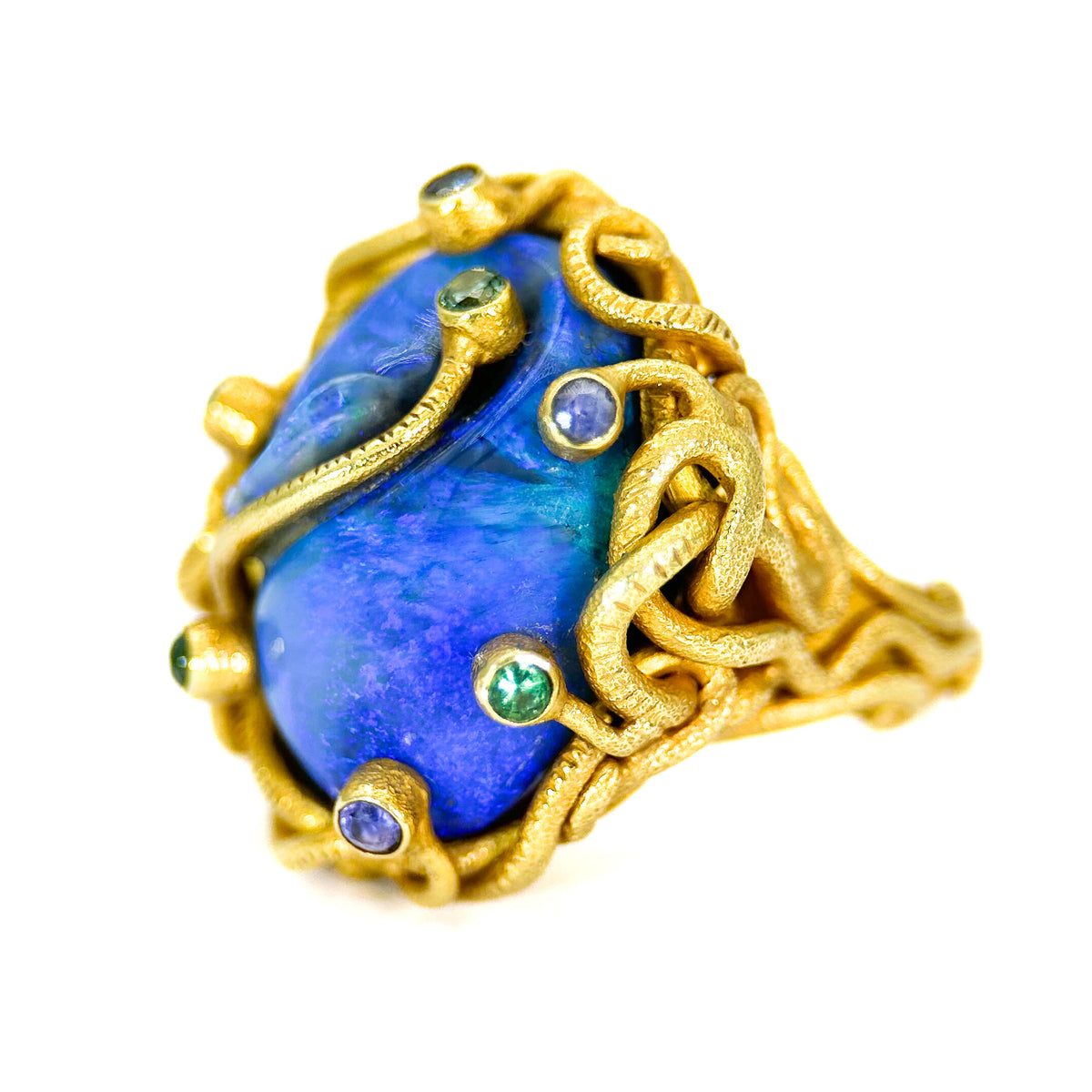 Gold ring with a blue stone and green gemstones on a white background
